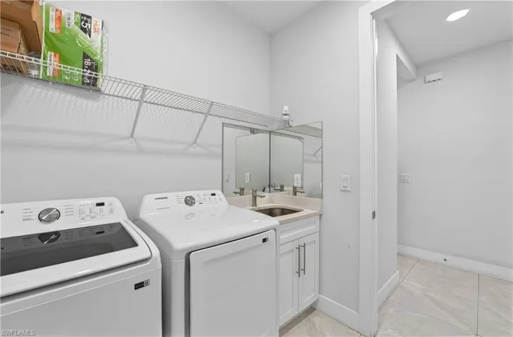Laundry room with washing machine and dryer, cabinet space, recessed lighting, and light marble finish floors