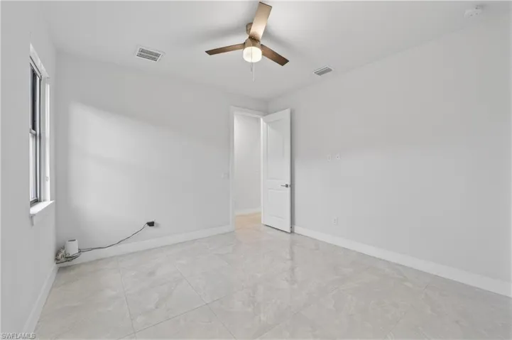 Empty room with a ceiling fan and light marble finish flooring