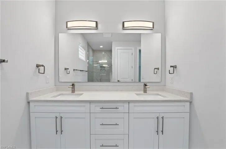 Full bath featuring double vanity and a shower stall