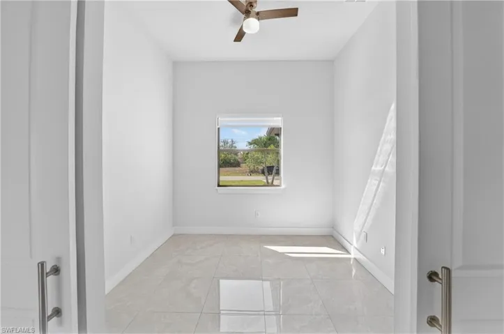 Empty room featuring ceiling fan and baseboards