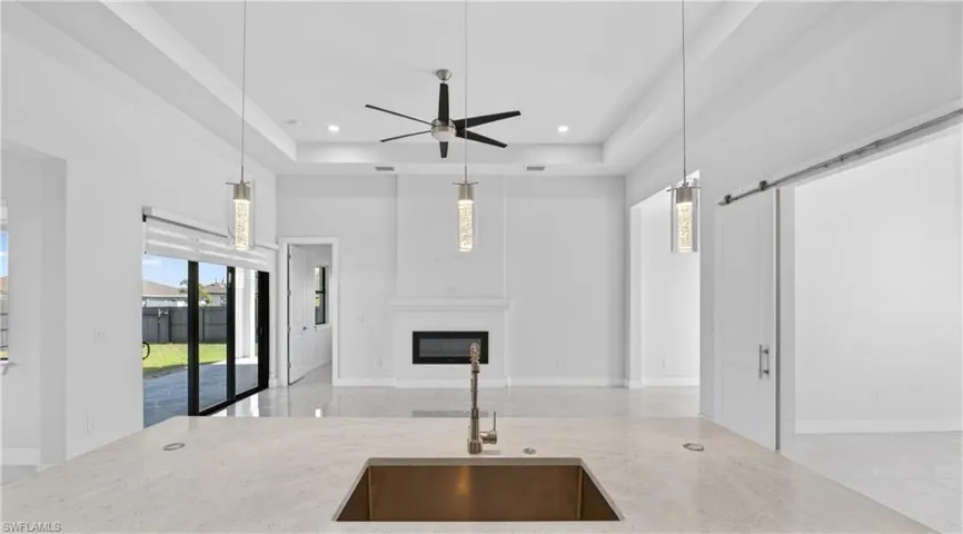 Kitchen with a glass covered fireplace, a barn door, hanging light fixtures, ceiling fan, and open floor plan