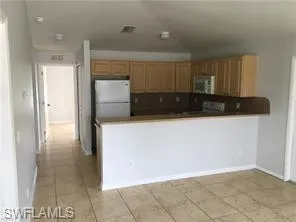 Kitchen featuring light wood cabinetry, white refrigerator, and stainless steel microwave
