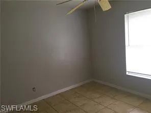 Room featuring neutral wall tones, tile flooring, a window with blinds, and a ceiling fan