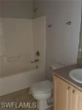 Bathroom featuring a white tub/shower combination, toilet, and a vanity with an integrated sink