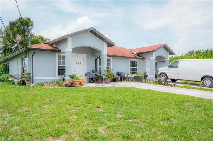 Light blue stucco exterior with a terra cotta-toned roof, featuring a covered entry porch