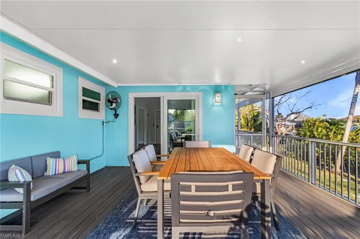 Spacious screened porch featuring a vaulted white ceiling, recessed lighting, and a vibrant turquoise accent wall