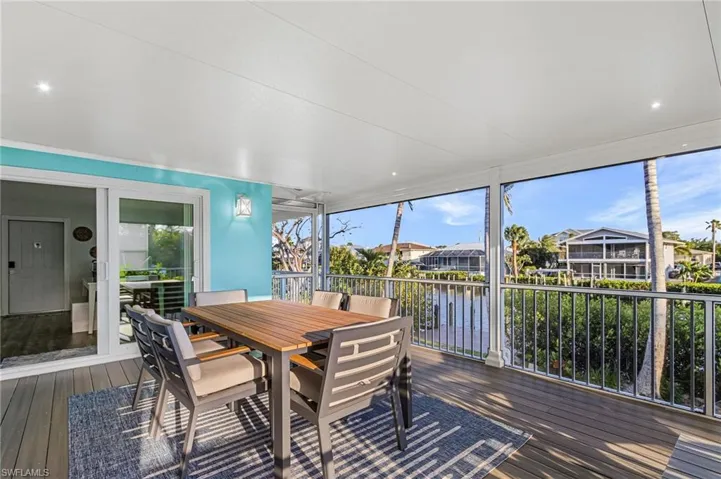 Screened lanai featuring water frontage, wood-finish decking, and recessed lighting