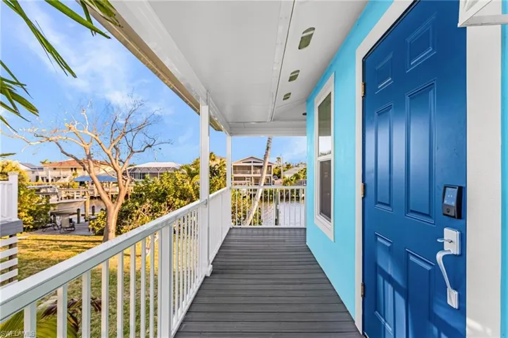 Covered porch featuring wood-finish decking and white railings