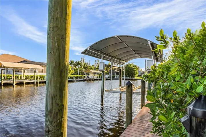 Canal-front property featuring a private boat dock with a covered boat lift