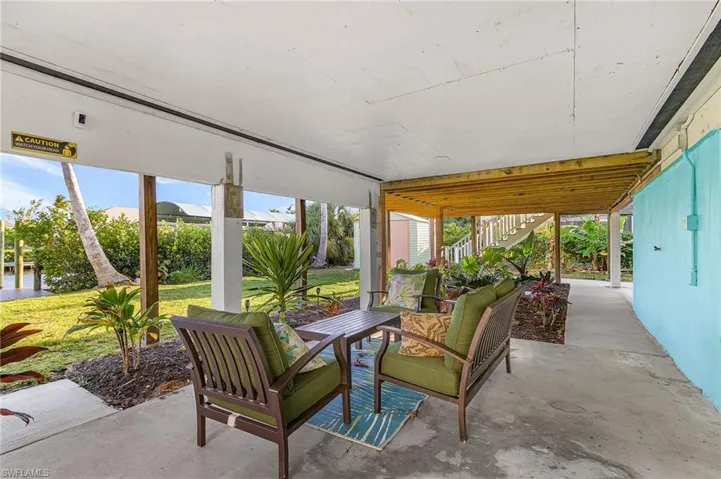 Covered patio space featuring a concrete slab, wooden support beams, and recessed lighting