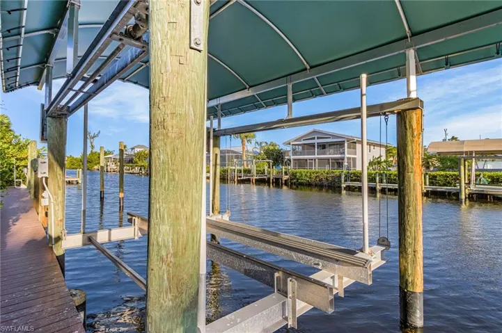 Waterfront property featuring a boat lift, covered dock, and a wood-finish dockside walkway