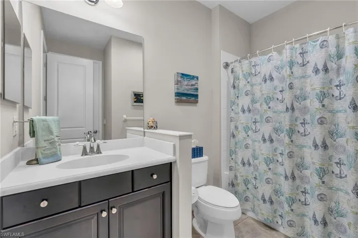 Full bathroom with shower / tub combo with curtain, tile patterned flooring, vanity, and toilet