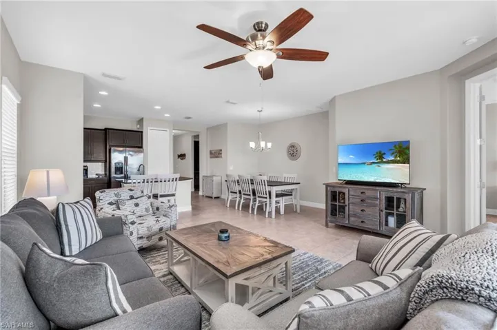 Tiled living room featuring ceiling fan with notable chandelier and radiator