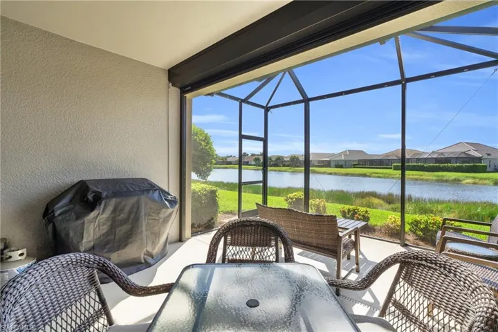 View of patio with a lanai, grilling area, and a water view