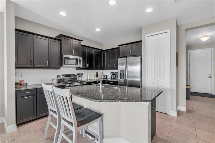 Kitchen with sink, tasteful backsplash, a center island with sink, appliances with stainless steel finishes, and dark stone countertops