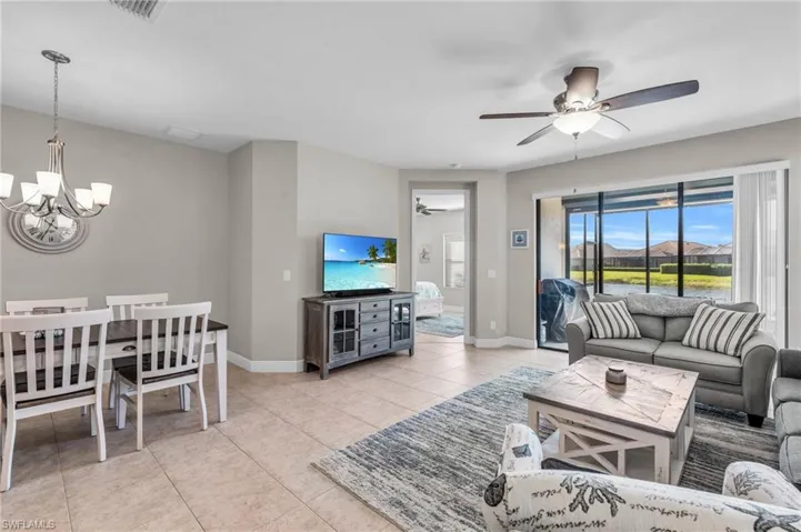 Living room with ceiling fan with notable chandelier and light tile patterned floors