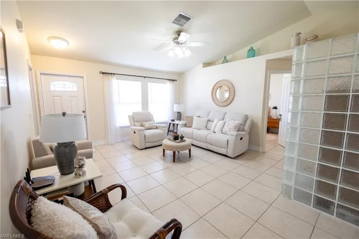 Living room with vaulted ceiling, ceiling fan, and light tile patterned floors