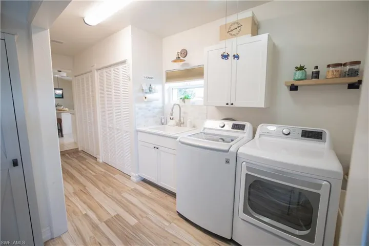 Laundry area featuring separate washer and dryer, cabinet space, and light wood-type flooring
