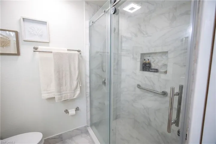 Master Bathroom featuring marble look tile flooring and a marble finish shower