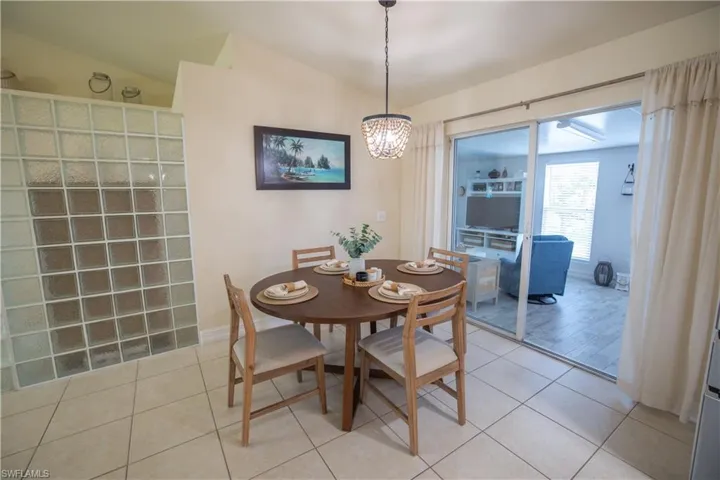 Dining area with lofted ceiling, light tile patterned floors, and a chandelier