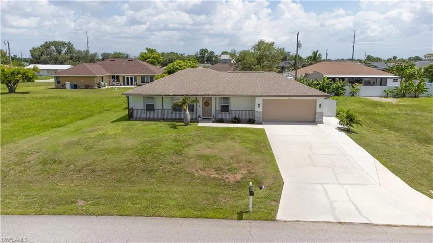 Ranch-style house with concrete driveway, an attached garage, a front lawn, a porch, and a residential view