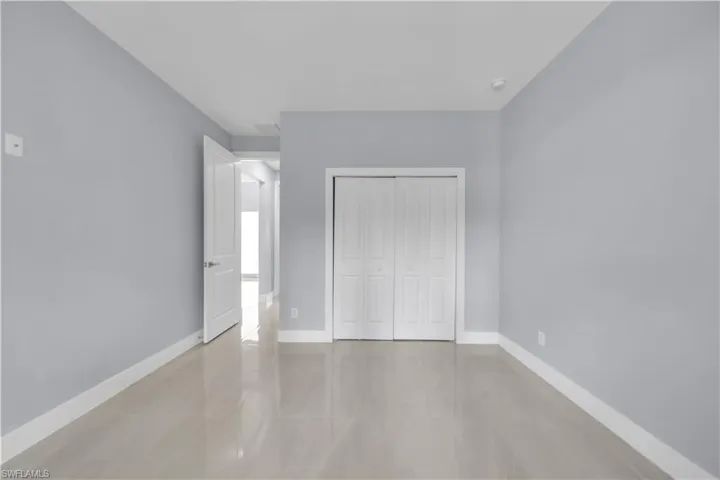 Light-colored wall paint with white trim, gloss tile flooring, and bi-fold closet doors