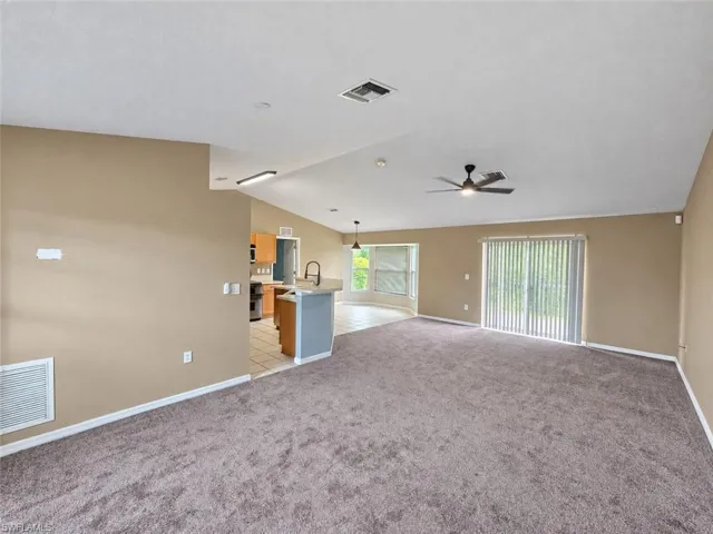 Expansive carpeted living area with a ceiling fan, sliding glass door, and recessed lighting