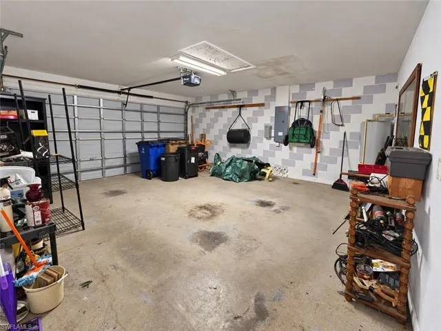 Concrete flooring, overhead garage door, built-in shelving, overhead lighting, patterned wall finish