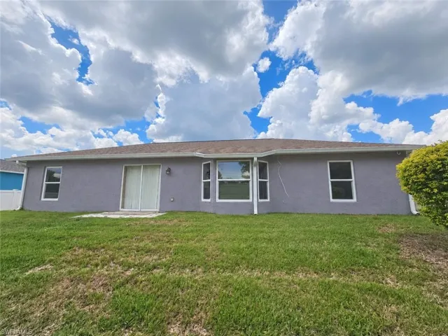 Exterior stucco finish with multiple windows and a sliding glass door