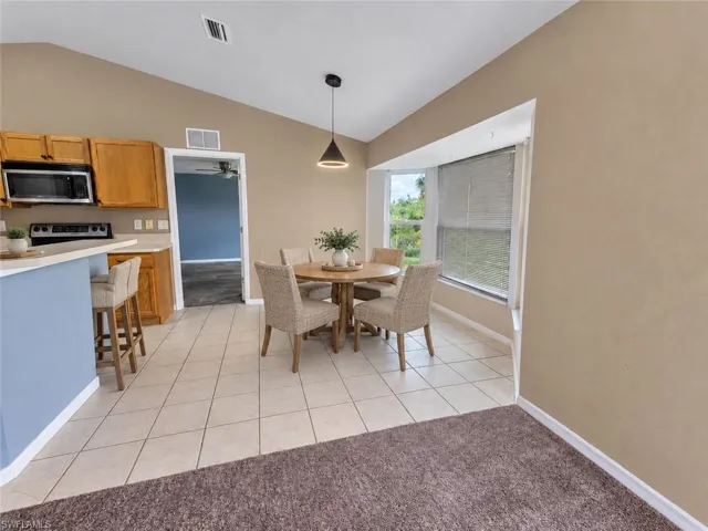 Vaulted ceiling over dining area with bay window and pendant lighting