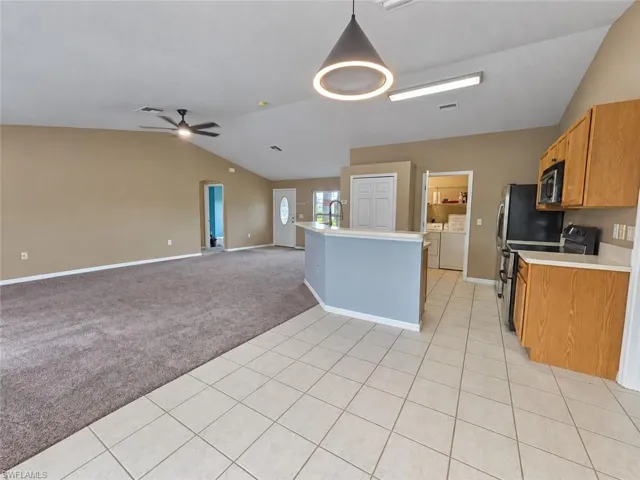 Vaulted ceiling, ceiling fan, wood-finish cabinetry, tile flooring, pendant lighting