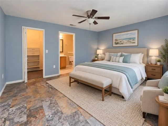 Ceiling fan, stone-finish flooring, light blue wall paint, closet with built-in shelving, and an en-suite bathroom with a vanity