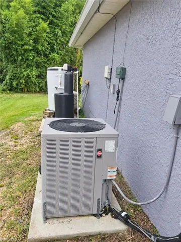 Exterior stucco finish, prominent HVAC unit, visible water softener system, and well pump