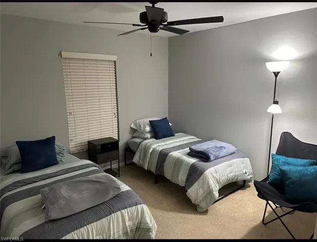 Carpeted bedroom with a ceiling fan