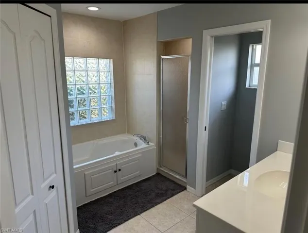 Bathroom featuring vanity, a stall shower, healthy amount of natural light, and light tile patterned floors