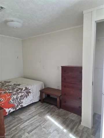 Bedroom with crown molding and a textured ceiling