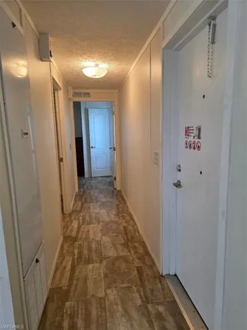 Hall with a textured ceiling, a heating unit, and stone finish flooring