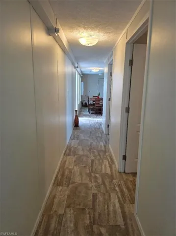 Hallway featuring a textured ceiling and a decorative wall