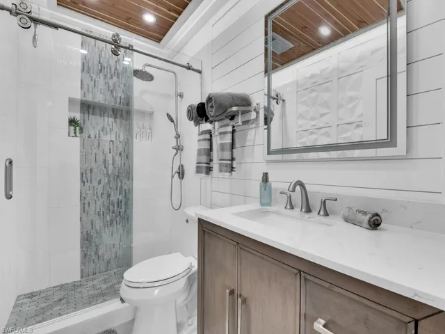 Bathroom with an enclosed shower, wood ceiling, shiplap walls, vanity, master lighting