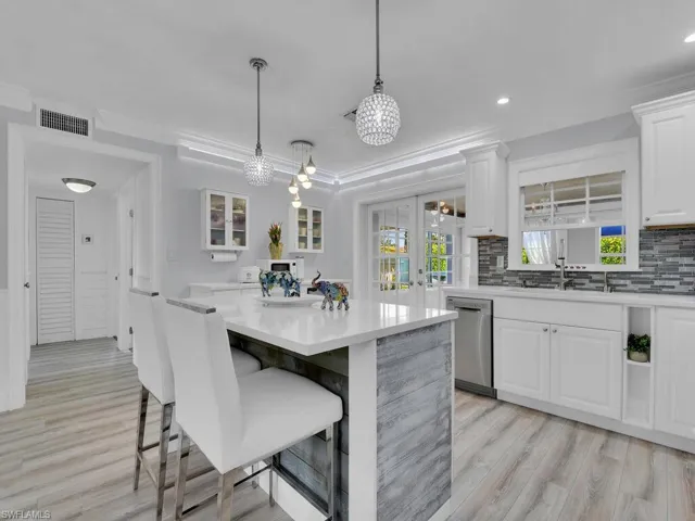 Kitchen with light hardwood / wood-style flooring, crown molding, tasteful backsplash, dishwasher, and hanging pendant fixtures and recessed lighting