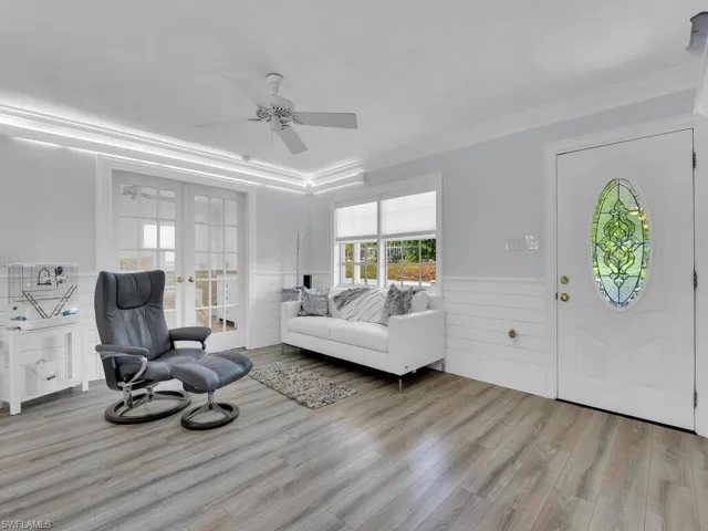 Living room with ceiling fan, light vinyl wood-style flooring, crown molding, Lutron lighting with "smarthub"