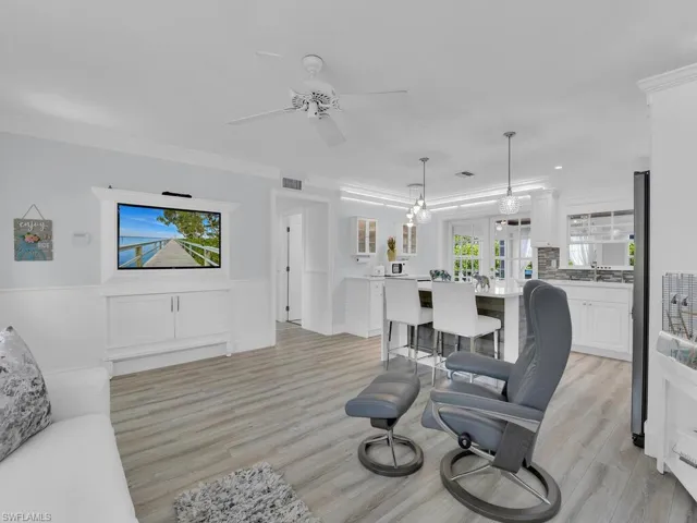 Living room with ceiling fan, light vinyl wood-style flooring, crown molding, Lutron lighting with "smarthub"