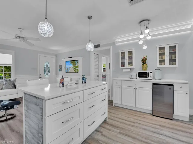 Ktchen island and coffee bar with light vinyl wood-style floors, crown molding, and pendant lighting