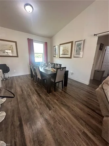 Dining area with lofted ceiling, dark wood-style floors, and a barn door