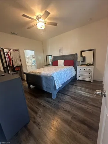 Bedroom with dark wood-style flooring, a ceiling fan, and ensuite bath