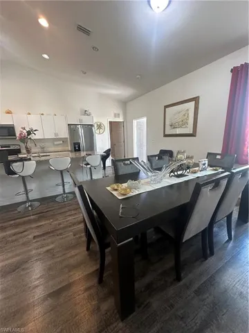 Dining space with dark wood finished floors and recessed lighting
