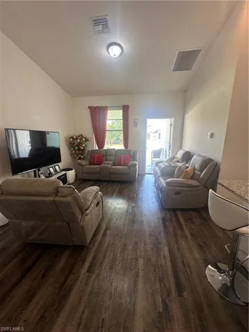 Living room featuring dark wood-style floors and vaulted ceiling