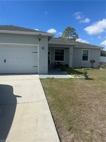 Single story home with a front yard, driveway, a shingled roof, and stucco siding