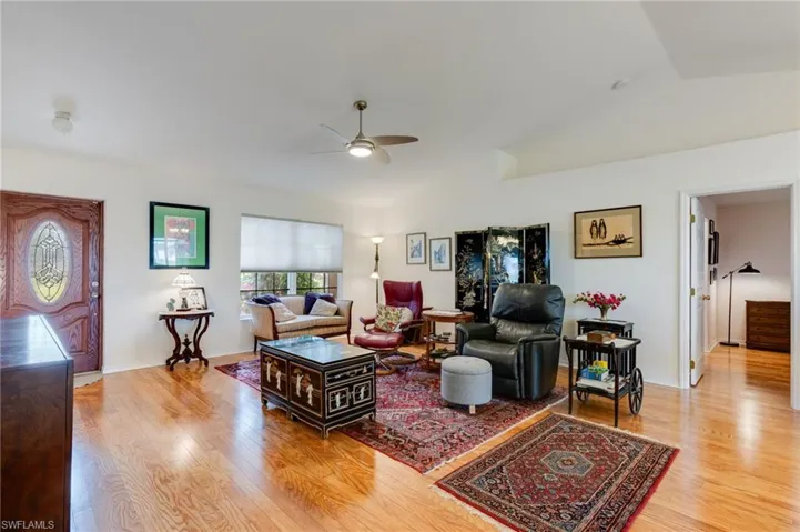 Living room with vaulted ceiling, ceiling fan, and light wood-style floors