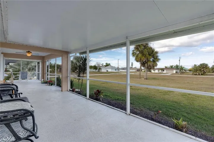 Unfurnished sunroom featuring ceiling fan and a residential view